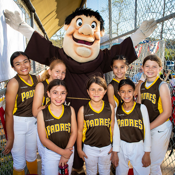 Girls in softball uniforms with Padres team mascot