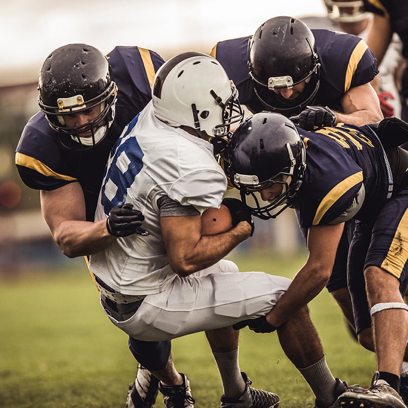 A football player is tackled by three defensive men 
