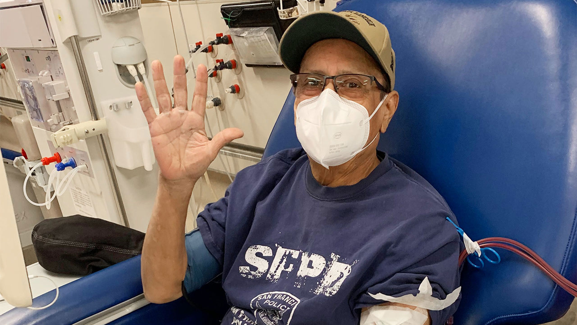 male patient waves while receiving dialysis treatment 